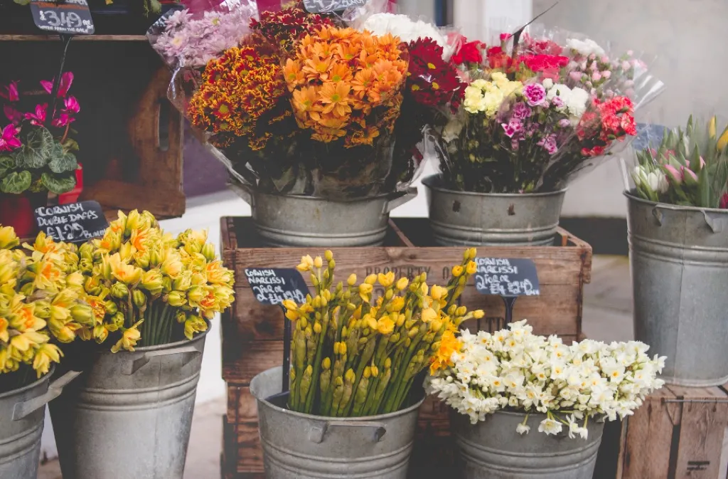 Metal buckets filled with fresh cut flowers at a florist's stall